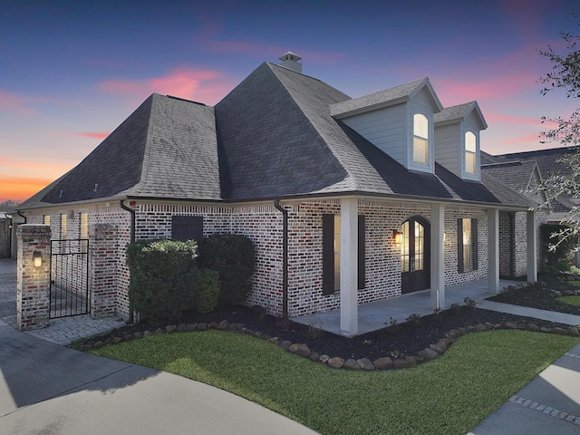 view of side of home featuring a chimney, a yard, a shingled roof, and brick siding
