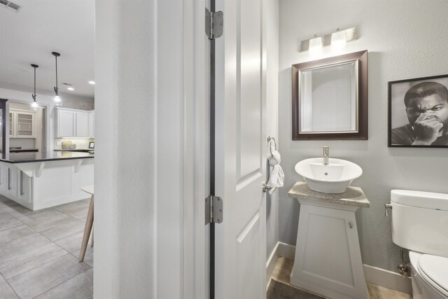 bathroom with tile patterned floors, toilet, vanity, baseboards, and visible vents