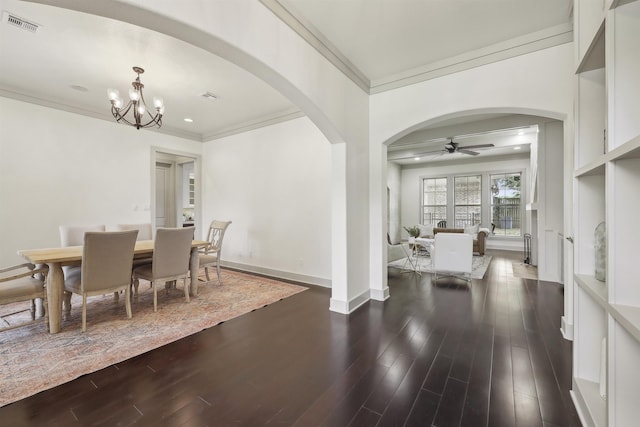dining room featuring crown molding, visible vents, arched walkways, dark wood-style flooring, and ceiling fan with notable chandelier