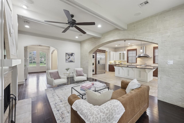 living area with visible vents, ceiling fan, light wood finished floors, and arched walkways