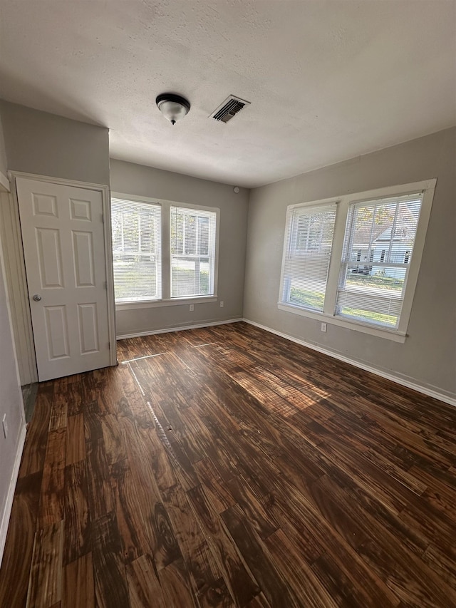 unfurnished room with plenty of natural light and dark hardwood / wood-style flooring