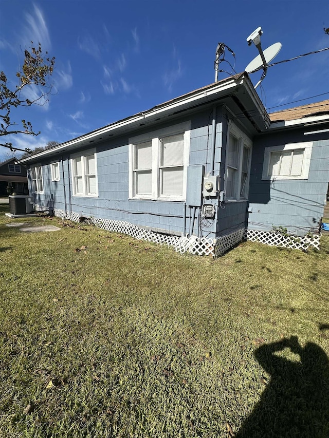 view of side of property featuring central AC and a yard