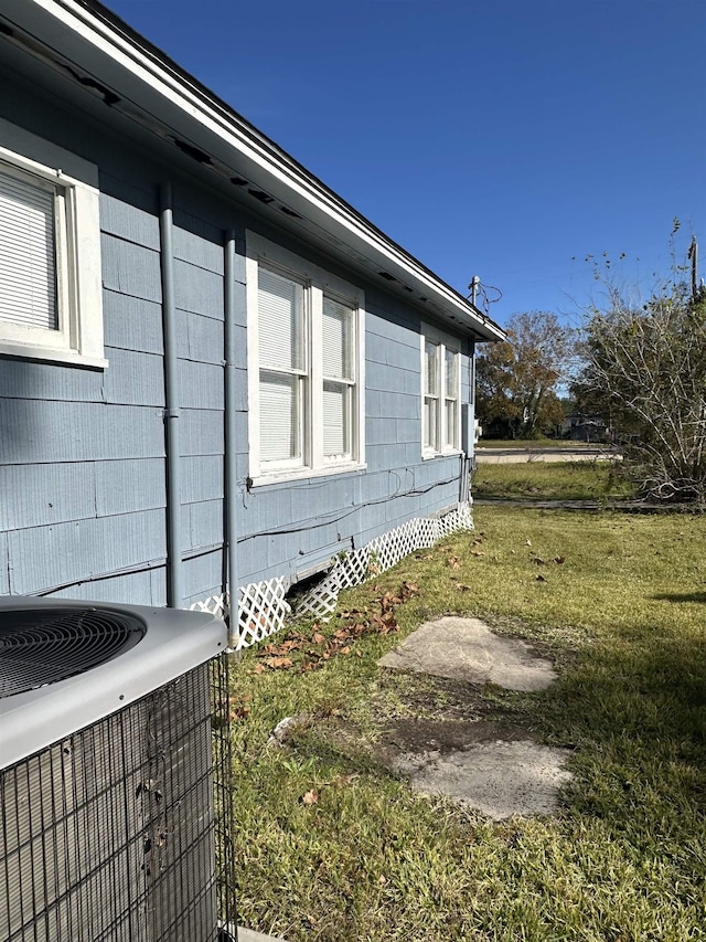 view of side of home with a yard and central AC