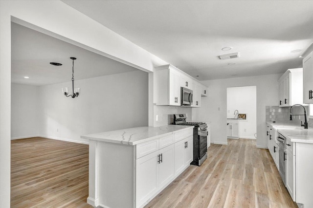 kitchen with white cabinetry, stainless steel appliances, tasteful backsplash, a notable chandelier, and pendant lighting