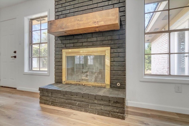 interior details with wood-type flooring and a brick fireplace