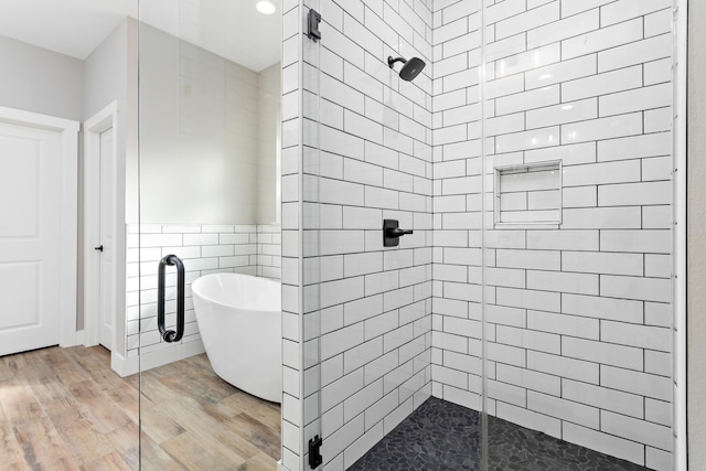 bathroom with hardwood / wood-style flooring, separate shower and tub, and tile walls