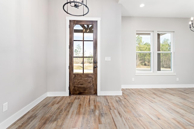 entryway with light hardwood / wood-style floors and an inviting chandelier