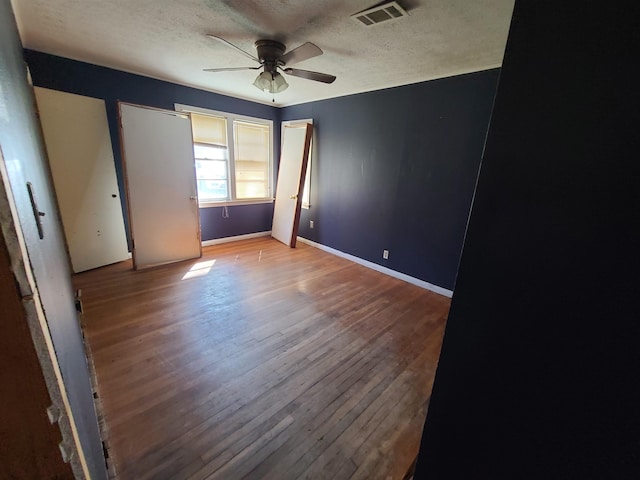 unfurnished bedroom featuring ceiling fan, wood-type flooring, and a textured ceiling