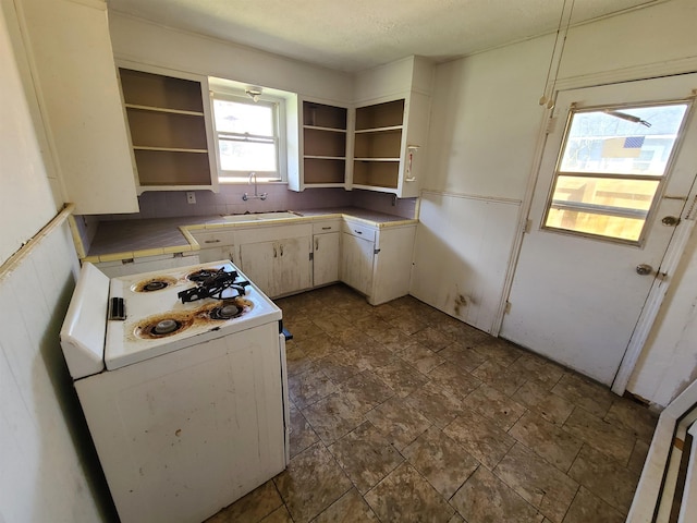 kitchen with tasteful backsplash, sink, white range with gas stovetop, and white cabinets