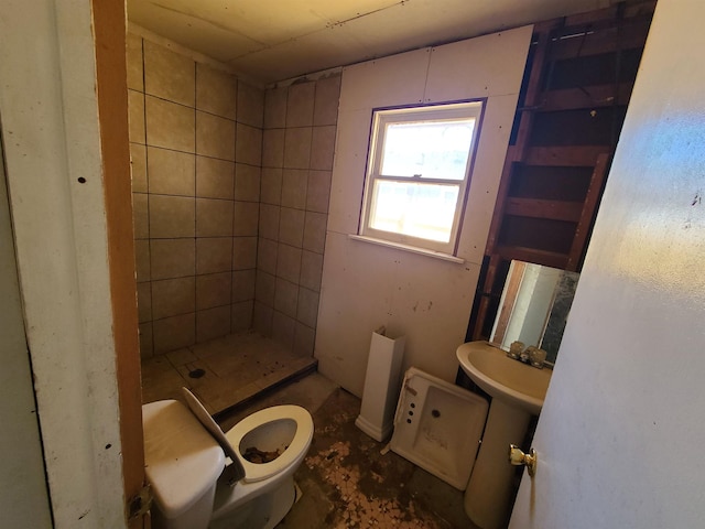 bathroom with sink, a tile shower, and toilet