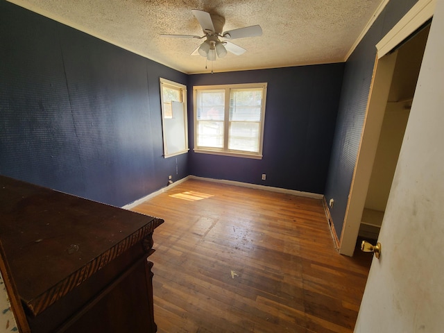 unfurnished bedroom with crown molding, ceiling fan, wood-type flooring, and a textured ceiling