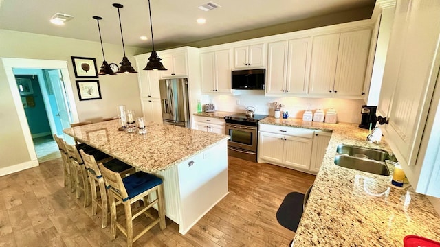 kitchen with a center island, white cabinetry, stainless steel appliances, and hanging light fixtures