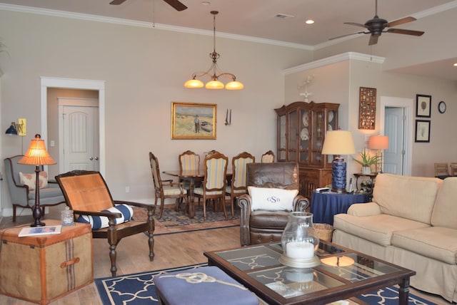 living room featuring crown molding, ceiling fan with notable chandelier, and light wood-type flooring