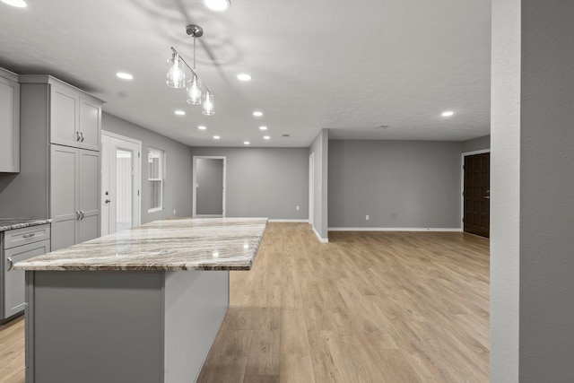 6425 Adams Blvd, Groves, TX 77619 - kitchen featuring gray cabinetry, a center island, recessed lighting, light stone counters, and light wood-type flooring
