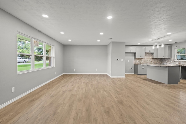 6425 Adams Blvd, Groves, TX 77619 - unfurnished living room with recessed lighting, light wood finished floors, and a textured ceiling