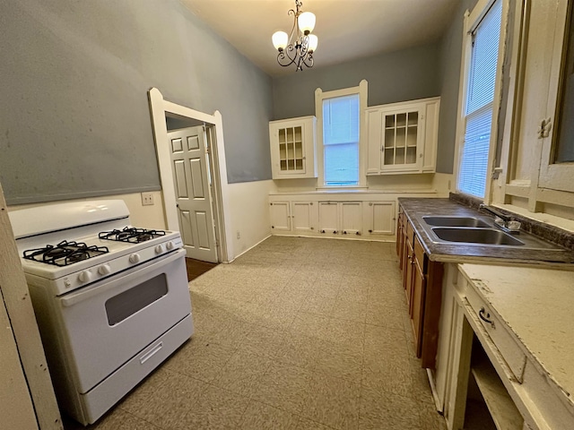 kitchen with white cabinetry, white gas stove, sink, a notable chandelier, and decorative light fixtures