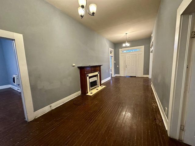 unfurnished living room with a tiled fireplace, dark hardwood / wood-style flooring, and a notable chandelier