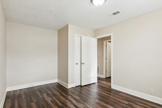 unfurnished room featuring a textured ceiling and dark wood-type flooring