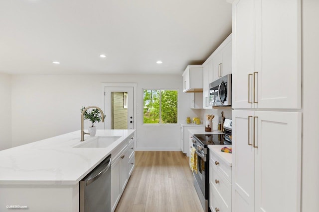 381 Perryman St, New Braunfels, TX 78130 - kitchen with white cabinetry, light stone counters, a sink, light wood finished floors, and appliances with stainless steel finishes
