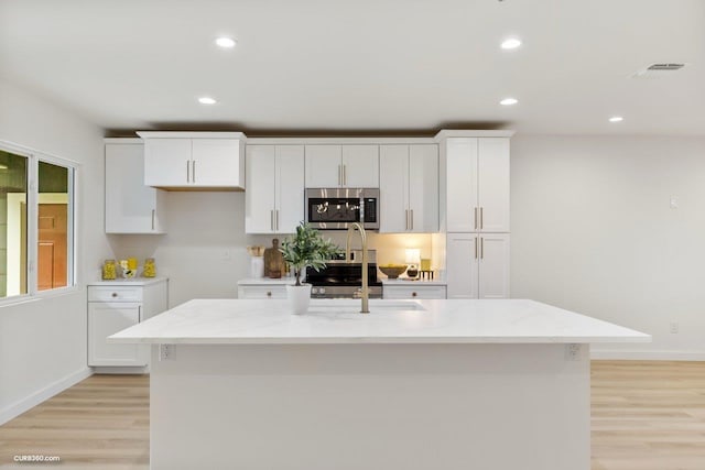 381 Perryman St, New Braunfels, TX 78130 - kitchen with light wood-style floors, appliances with stainless steel finishes, white cabinets, and visible vents