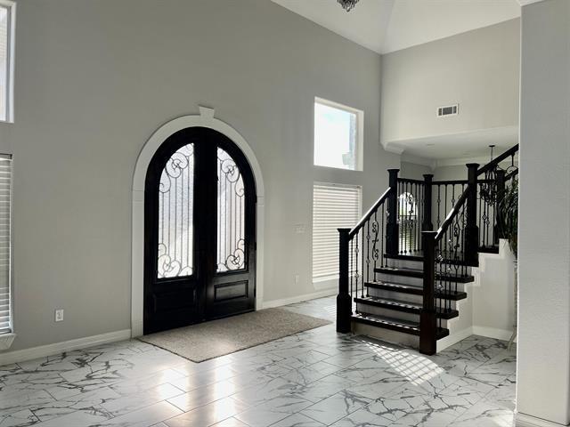 7600 Oakmont Dr, Port Arthur, TX 77642 - foyer entrance featuring marble look tile flooring, a towering ceiling, arched walkways, and baseboards