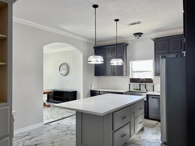 7600 Oakmont Dr, Port Arthur, TX 77642 - kitchen featuring light marble finish floors, a sink, stainless steel appliances, light countertops, and arched walkways