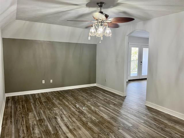 7600 Oakmont Dr, Port Arthur, TX 77642 - spare room featuring arched walkways, dark wood-type flooring, ceiling fan, baseboards, and lofted ceiling