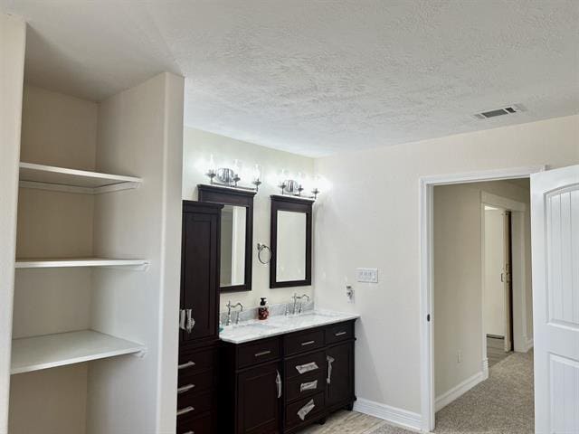7600 Oakmont Dr, Port Arthur, TX 77642 - bathroom featuring double vanity, a textured ceiling, and baseboards
