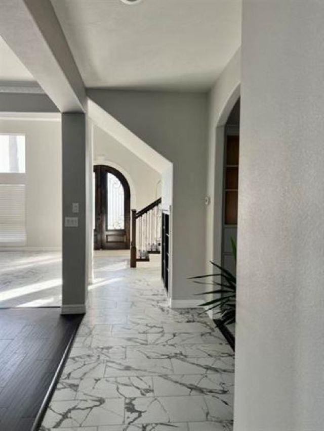 7600 Oakmont Dr, Port Arthur, TX 77642 - hall featuring arched walkways, marble look tiles, healthy amount of natural light, and stairs