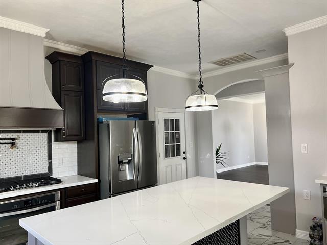 7600 Oakmont Dr, Port Arthur, TX 77642 - kitchen with stainless steel appliances, a kitchen island, baseboards, backsplash, and ornamental molding