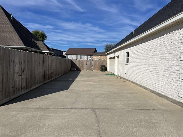 7600 Oakmont Dr, Port Arthur, TX 77642 - view of side of home with a fenced backyard, driveway, a patio area, and a garage