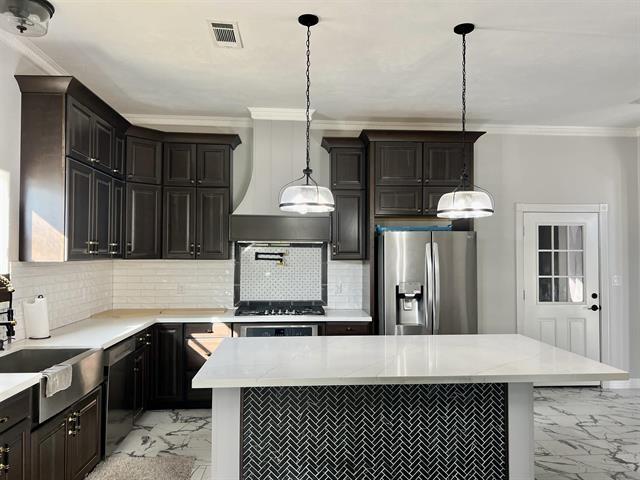 7600 Oakmont Dr, Port Arthur, TX 77642 - kitchen featuring stainless steel appliances, light marble finish flooring, crown molding, light countertops, and tasteful backsplash
