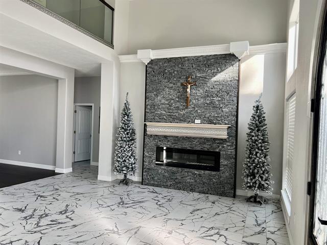 7600 Oakmont Dr, Port Arthur, TX 77642 - living room featuring marble tiled floors, baseboards, a fireplace, and a high ceiling