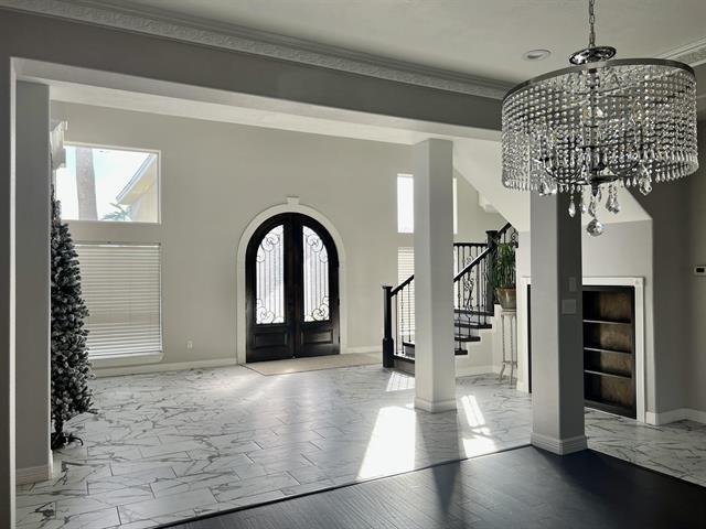 7600 Oakmont Dr, Port Arthur, TX 77642 - foyer with stairs, marble look tiles, french doors, healthy amount of natural light, and ornamental molding