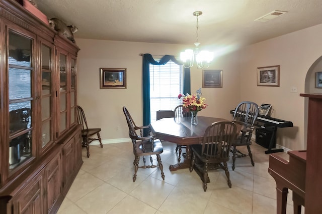 dining room with light tile patterned flooring, arched walkways, baseboards, a notable chandelier, and visible vents