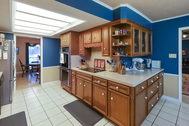 kitchen featuring brown cabinets, light countertops, light tile patterned floors, and black appliances