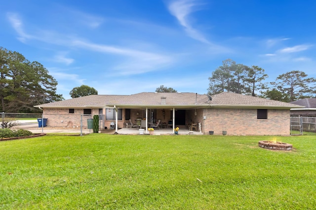 back of property featuring a yard, a patio area, fence private yard, a fire pit, and brick siding