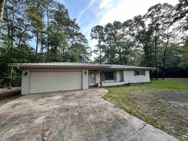 102 Ash Ln, Village Mills, TX 77663 - exterior space with a garage, cooling unit, metal roof, and brick siding