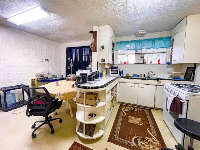 3832 W Park Ave, Orange, TX 77630 - kitchen featuring gas range gas stove, open shelves, white cabinets, a textured ceiling, and tile countertops