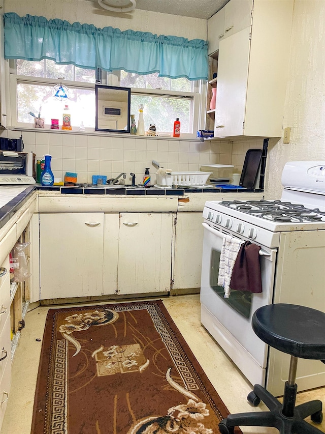 3832 W Park Ave, Orange, TX 77630 - kitchen with white gas stove, tile counters, white cabinetry, tasteful backsplash, and open shelves