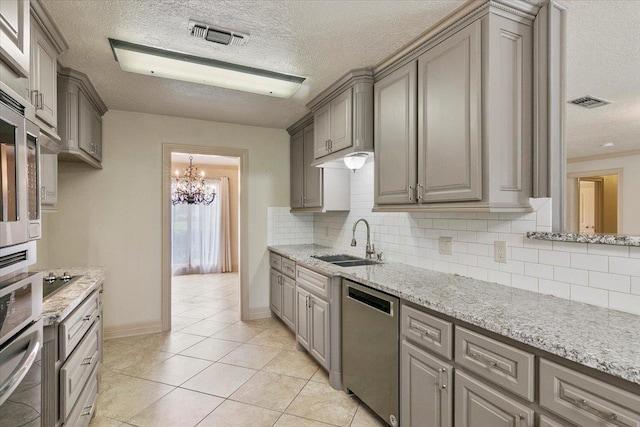 kitchen with sink, backsplash, a chandelier, light tile patterned floors, and appliances with stainless steel finishes