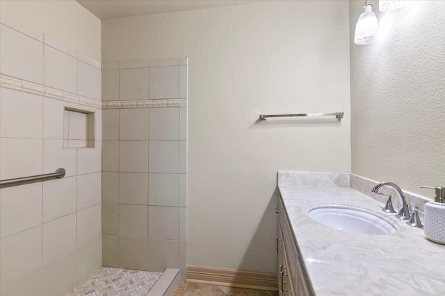 bathroom with a tile shower and vanity