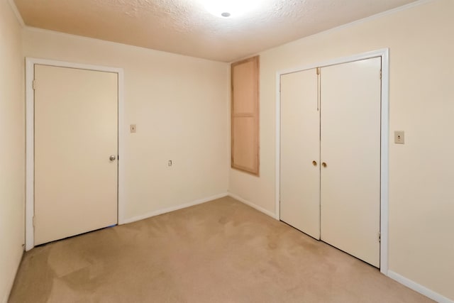 unfurnished bedroom with light carpet, a textured ceiling, and a closet