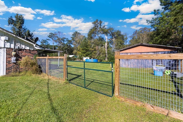 view of gate featuring a lawn and an outbuilding