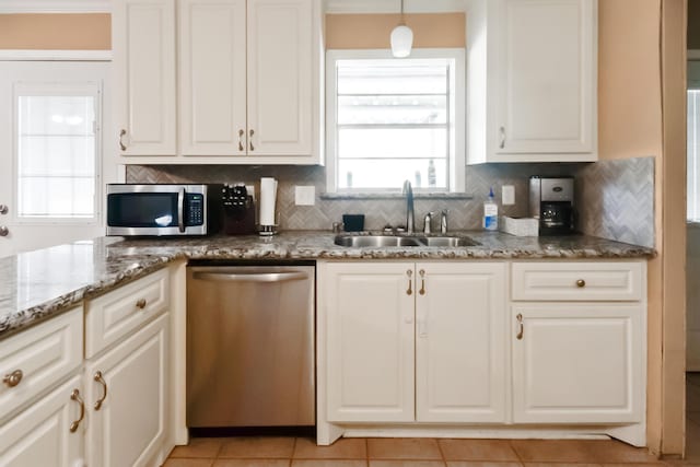 kitchen with hanging light fixtures, sink, decorative backsplash, appliances with stainless steel finishes, and light tile patterned flooring