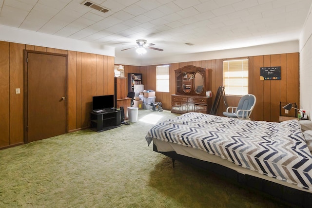 carpeted bedroom with ceiling fan and wooden walls