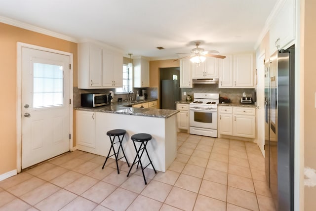 kitchen with light tile patterned floors, kitchen peninsula, stainless steel appliances, and dark stone counters