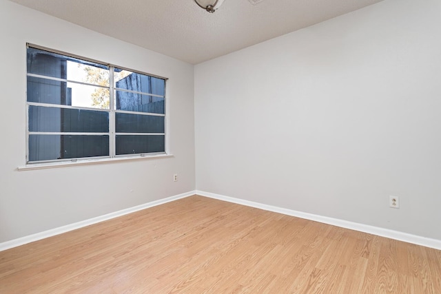 empty room with light wood-type flooring and a textured ceiling