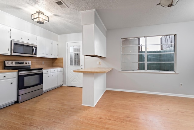 kitchen featuring white cabinets, decorative backsplash, stainless steel appliances, and light hardwood / wood-style flooring