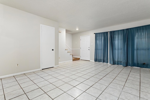 tiled spare room featuring a textured ceiling